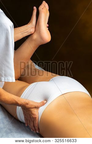 Top View Of Physiotherapist Applying Pressure On Female Buttock With Thumb. Woman Lying On Spa Bed H
