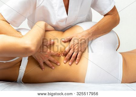 Close Up Of Physiotherapist Manipulating Female Lower Spine. Rear View Of Girl Laying On Spa Bed On 