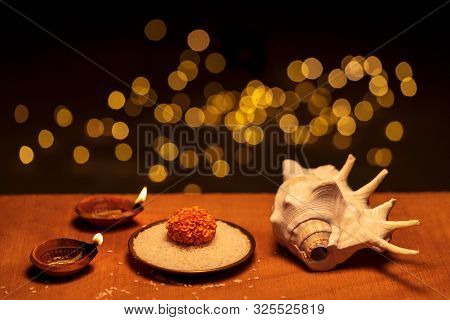 Diwali Festive Decoration With Diya Oil Lamps, Flowers, Rice Grains And Hindu Religious Conch Shell 