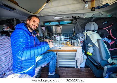 Making Breakfast Or Lunch In Campervan, Motorhome Or Rv. Young Hipster Guy Preparing Food In Camper 