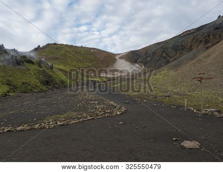 Hiker With Blue Backpack And Tourist Signpost At Laugavegur Trek In Colorful Rhyolit Rainbow Mountai