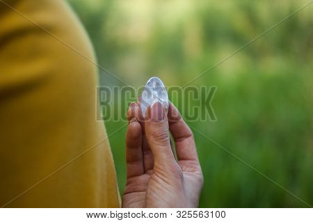 Adult Girl In Yellow Shirt And Blue Jeans Is Holding Transparent Violet Amethyst Yoni Egg For Vumfit