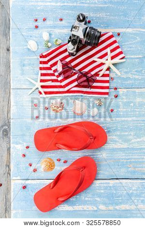 Red Summer background with camera starfish sandle sunglasses on blue wooden table background with copy space