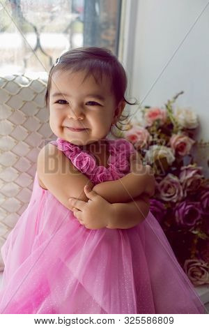 Girl Child In A Dress Sitting On The Window