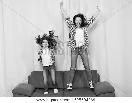 Happy Family Celebrating Mothers Day. Happy Mother And Daughter Jumping On Sofa. Mother And Child En