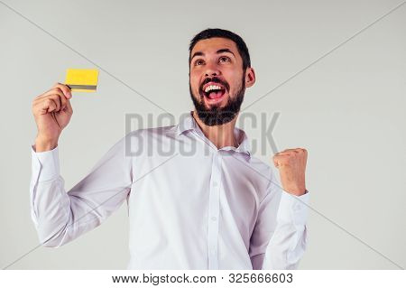 Business Man In A White Shirt Holding Yellpw Credit Card . Looking At Camera, Smiling . Black Friday