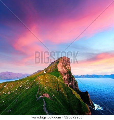 Incredible sunset landscape with Kallur lighthouse on green hills of Kalsoy island, Faroe islands, Denmark