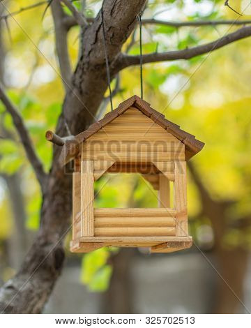 Wooden Homemade House Hanging On A Tree, Bird Feeder. Small Log House With Large Windows For Feeding