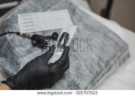 Machine For Permanent Makeup In The Hand Of The Master In A Black Glove And A Disposable Needle