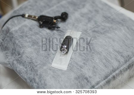 A Permanent Make-up Machine And A Disposable Needle Lie On A Couch