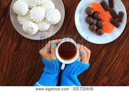Woman's Hands, A Mug Of Tea. Marshmallows, Marmalade, Candies On The Plates