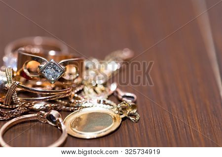 Real Gold Rings With Diamonds, Gems, Neckless On Dark Cracked Wood Background Close Up Macro Shot.