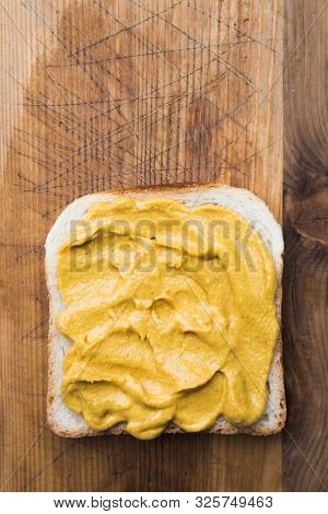 Slice of toast bread with mustard spread shot from above