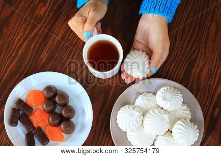 Woman's Hands With A Mug Of Tea And Marshmallows, A Plate Of Marshmallows, A Plate Of Sweets And Mar