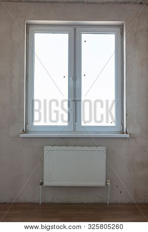 View Of The Window And The Battery Under The Window In The Interior Of An Unrepaired Room