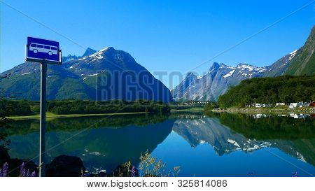 Reflections Of Beautiful Mountains With Snow, Forest And Bare Rock And Blue Sky Are Seen In The Flow