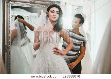 Beautifu bride choosing wedding dress in a wedding salon