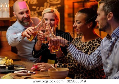 Group of friends playing sticky head game behind bar counter in a cafe