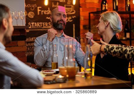 Group of friends playing sticky head game behind bar counter in a cafe