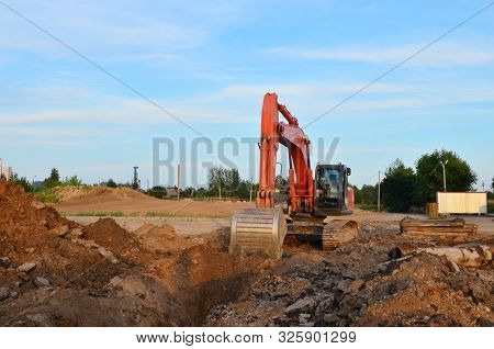Crawler Excavator In Construction Site On The Background Of Tower Cranes And Multi-storey Residentia