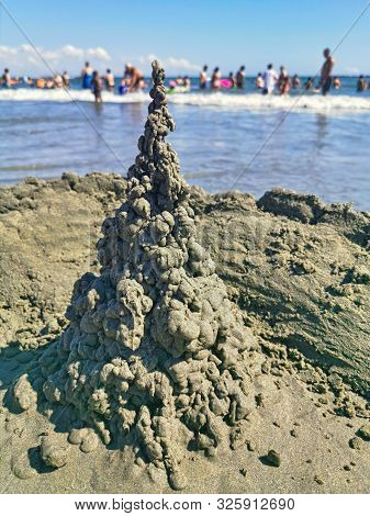 Wet Sand Castle And Blurred Croded Beach Background