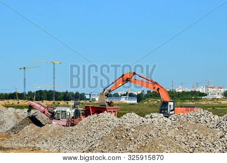 Heavy Tracked Excavator Load Stone, Old Asphalt Or Concrete Waste Into A Mobile Jaw Crusher Machine.