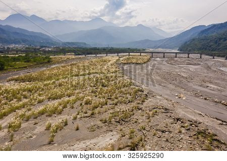 landscape of golden miscanthus with mountain and river under sky