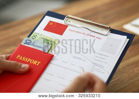 Male Hand Hold Silver Pen With Passport. Filling China Apllication Form Concept