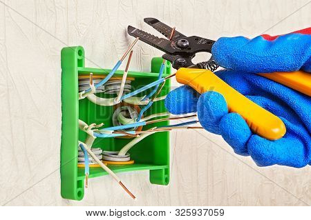 A Hand In A Blue Protective Glove Holds A Cutter To Cut Off The Ends Of Electric Copper Wires. Insta