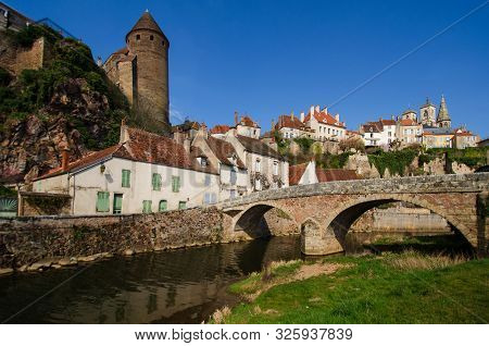 View Of The Small Town Of Semur-an-osois, Burgundy, France. There Is An Embankment And A Bridge Acro