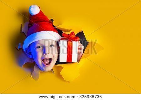 Little Cheerful Santa Gives A Gift, Getting Out Of The Ragged Yellow Background