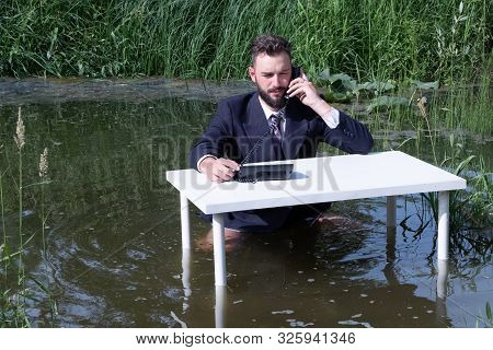 Office Worker In The Swamp. A Young Guy With A Beard In A Suit With A Tie. A Clerk, Official Or Busi
