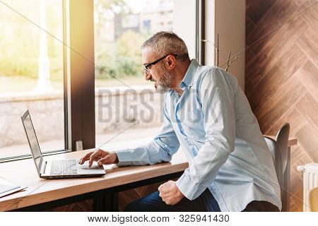 Handsome Middle Aged Man Working On Computer In A Cafe. Business, Modern Concept