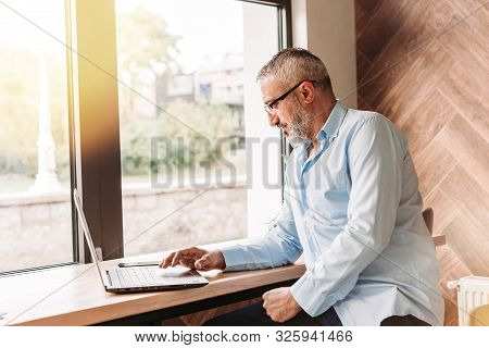 Handsome Middle Aged Man Working On Computer In A Cafe. Business, Modern Concept
