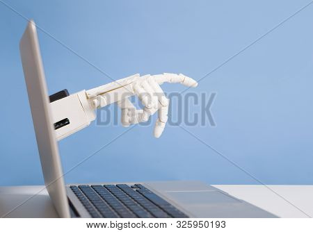 Robotics Invasion Into Real Life. Robot Hand Reaching Out Of Laptop Screen, Blue Background