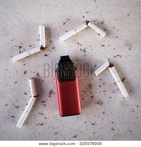Single Red Vape Electronic Cigarette As Smoking Alternative With Broken Cigarettes And Scattered Tob