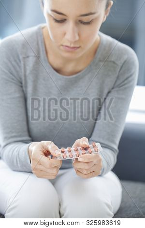Young Woman Pushing Pill Out Of Blister Package