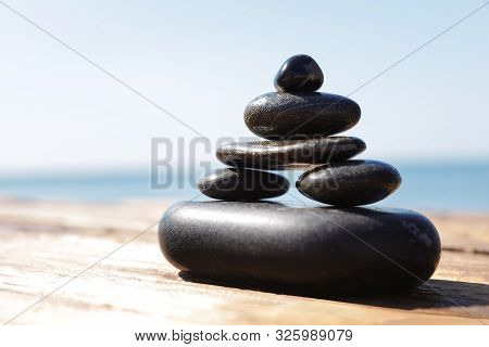 Stack Of Stones On Wooden Pier Near Sea, Space For Text. Zen Concept