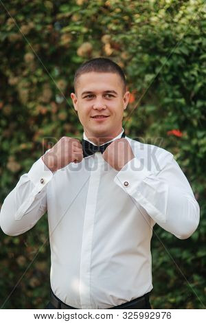Young Man In White Shirt With Black Tie Bow Stand Outside