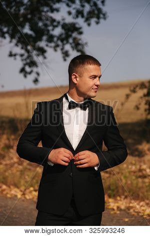 Young Man Walking In The Park. Handsome Groom In Black Suit