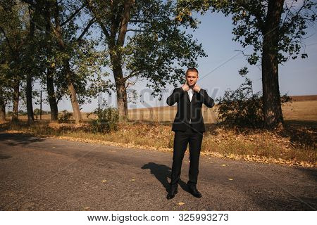 Young Man Walking In The Park. Handsome Groom In Black Suit
