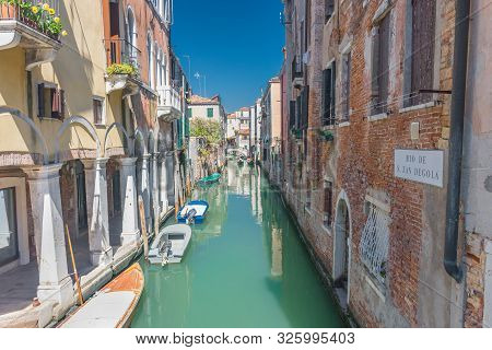 Canal (rio De S. Zan Degola) With Boats, Gondolas And Historic Houses, In Venice, Italy, In A Beauti