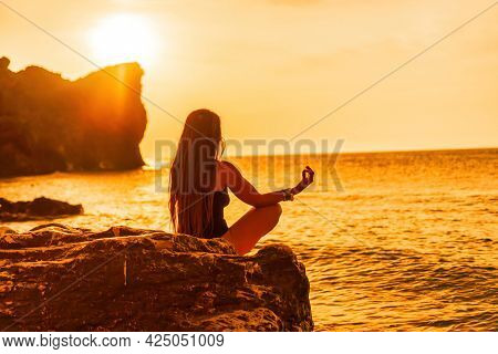 Young Woman With Long Hair In Black Swimsuit And Boho Style Braclets Practicing Outdoors On Yoga Mat