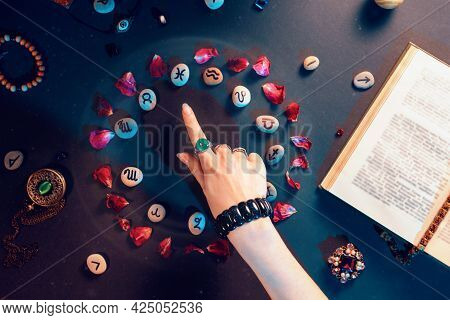 Concept Of Astrology And Horoscope. A Woman's Hand Points To The Stones With The Signs Of The Zodiac