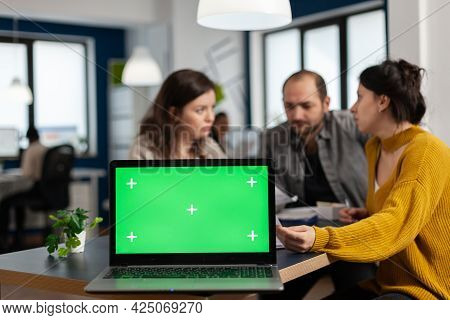 Businesspeople Analysing Annual Financial Reports Sitting At Desk In Back Of Laptop With Green Scree