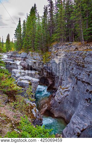 Maligne Canyon is the most unusual and interesting gorge in the Canadian Rockies. Travel to the Rocky Mountains. Cool cloudy day. The sheer canyon walls and the seething icy water below