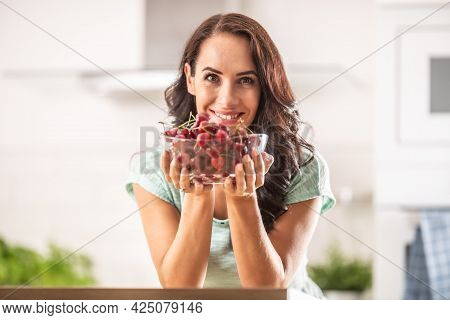 Fresh Fruit Harvest In The Form Of Cherries In A Seethrough Bowl Held By A Woman Indoors.