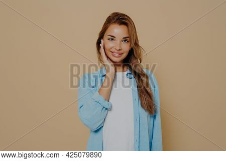 Portrait Of Attractive, Charming Brunette Female With Long Stright Hair. Wearing Blue Shirt Over Whi