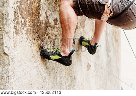 Legs And Feet Of Irrecoverable Climber Holding On To The Rock While Climbing A Mountain. Climbing Eq
