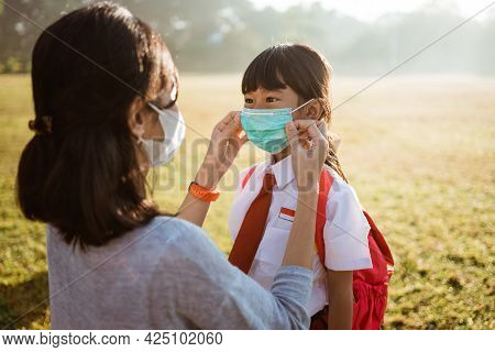 Mother Help Her Daughter To Put On The Mask Before Going To School